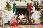 A boy sitting by a fireplace at Christmas