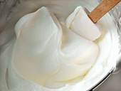 Whipped cream in mixing bowl with spatula