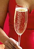 Frau in rotem Kleid hält Champagnerglas
