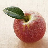 Red apple with stalk, leaf and drops of water