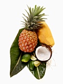 Pineapple, papaya, coconut and limes on palm leaf