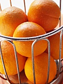 Oranges with drops of water in wire basket