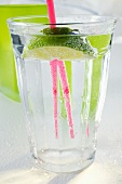 Glass of water with wedge of lime and straw