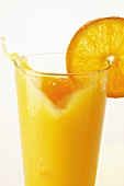 Orange juice splashing out of glass