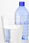 Mineral water in glass in front of plastic bottle