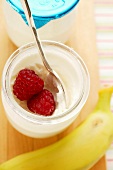 Jar of yoghurt with fresh raspberries; banana