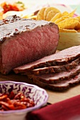 Roast beef on chopping board; tortilla chips