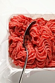 Fresh minced beef in plastic container with spoon