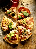 Pieces of pizza with different toppings, on wooden background