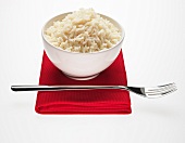 Bowl of long-grain rice and fork on red napkin
