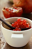 Pomegranate seeds in small bowl with spoon