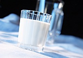 Glass of milk in front of glass jug