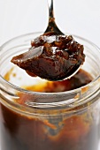 Game stock (demi-glace) in spoon above jar