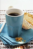 Blaue Espressotasse und leeres Muffin-Papierförmchen