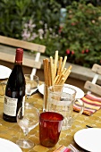 Sommerlicher Tisch mit Rotwein und Grissini im Freien