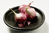 Three red onions in black bowl