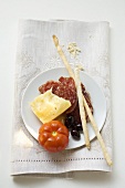 Salami, cheese, olives, tomato and grissini on plate