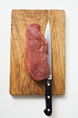 Beef sirloin with knife on chopping board