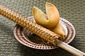 Fortune cookies and chopsticks in woven wrapper on plate