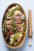 Duck breast on rice noodles with green asparagus