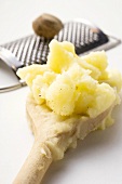 Mashed potato on wooden spoon, nutmeg with grater
