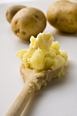 Mashed potato with butter on wooden spoon
