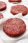 Several raw burgers on paper