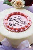 Birthday cake on pale purple box, roses (close-up)