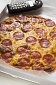 Whole salami and cheese pizza in pizza box with telephone