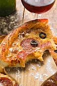 Piece of pizza with salami, cheese & olives (bites taken)