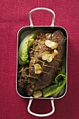 Roast lamb with garlic and vegetables in roasting dish