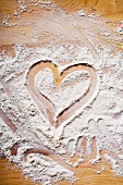 In Mehl gezeichnetes Herz auf Holzuntergrund