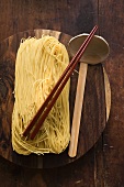 Egg noodles on wooden plate with chopsticks and ladle