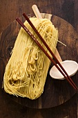 Egg noodles on wooden plate with chopsticks and ladle