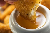 Dipping a chicken nugget in apricot sauce