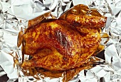 Half a grilled chicken on aluminium foil