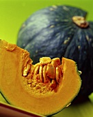 Wedge of pumpkin in front of pumpkin with piece cut out