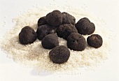 Several black truffles lying on rice