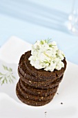 A pile of pumpernickel rounds with herb quark