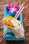 Rice paper roll with soy sauce, chopsticks and orchid