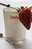 Beaker with the word 'love' and fondue fork with strawberry