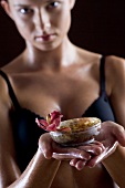 Young woman holding small bowl of body butter with orchid