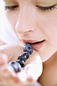 Young woman with a row of blueberries on her hand