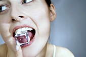 Junge Frau mit Eiswürfel im Mund