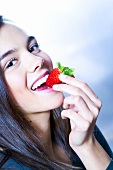 Junge Frau beisst in eine Erdbeere