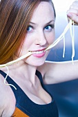 Sporty young woman holding spaghetti in her mouth