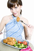Young woman eating breaded chicken