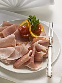 Various types of ham on a plate with meat fork