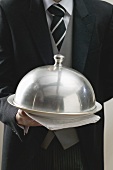 Waiter serving dish under dome cover