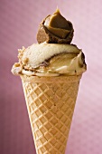 Caramel ice cream in wafer cone against pink background